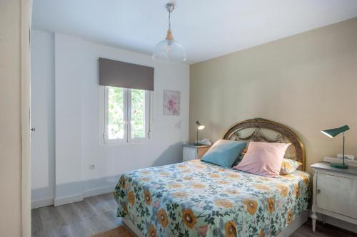 a bedroom with a bed with a floral bedspread and a window at Casa Valentina: Confort y Luz en Sevilla Centro in Seville