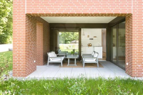 ein Backsteingebäude mit einer Terrasse mit Stühlen und einem Tisch in der Unterkunft Ferienwohnung Rosenstrasse in Dornbirn