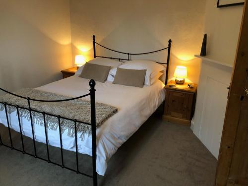 a bedroom with a bed with white sheets and two lamps at Hyde Mill in Luton