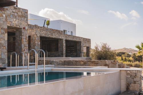 a villa with a swimming pool in front of a building at Kouros Blanc Resort & Suites in Pounda