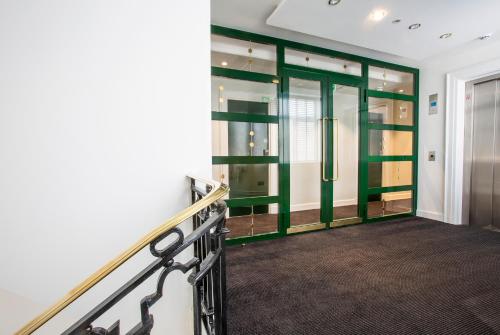 a hallway with green glass doors and a staircase at Astor Court Hotel in London