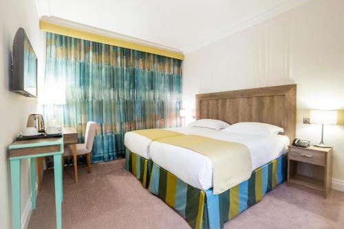 a hotel room with a large bed and a desk at Astor Court Hotel in London