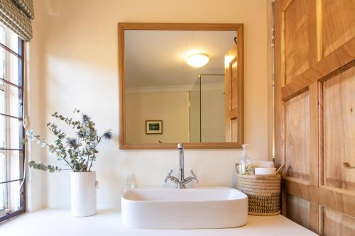 La salle de bains est pourvue d'un lavabo et d'un miroir. dans l'établissement Sunbird Cottage, à Graaff-Reinet