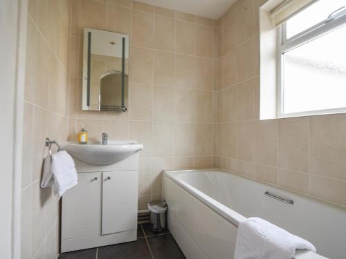 a bathroom with a tub and a sink and a mirror at Hollycombe Cottage in Wootton Fitzpaine