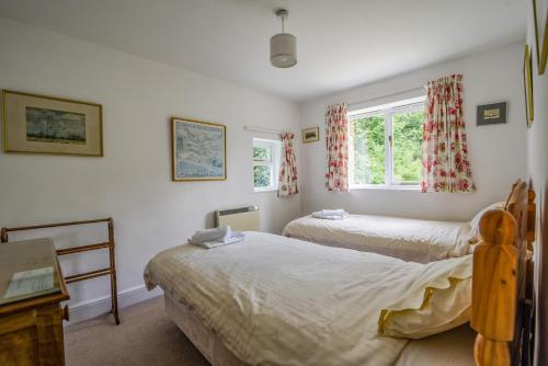 a bedroom with two beds and a window at Greystones Cottage in Chideock