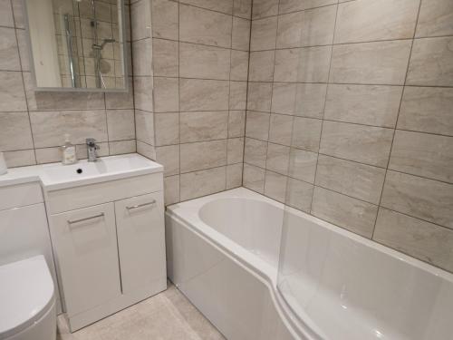 a bathroom with a tub and a toilet and a sink at East Barn in Wootton Fitzpaine