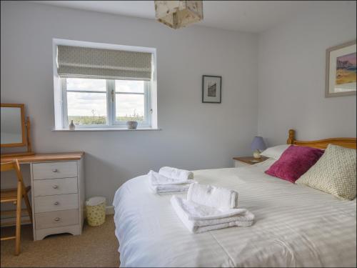 a bedroom with a bed with towels on it at East Barn in Wootton Fitzpaine