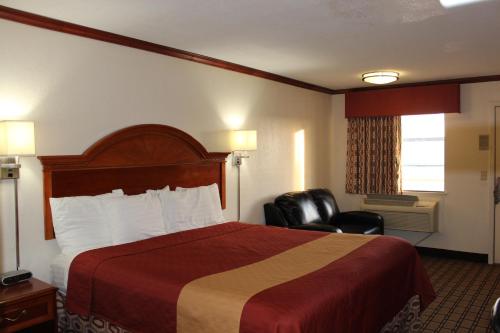 a hotel room with a bed and two chairs at Sanger Inn in Sanger