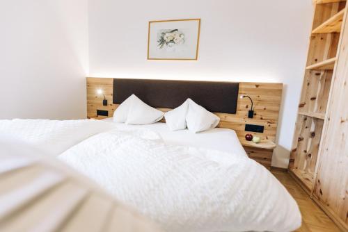 a white bed with white sheets and pillows in a bedroom at Amplatz 1523 - B&B and Suites in Montagna