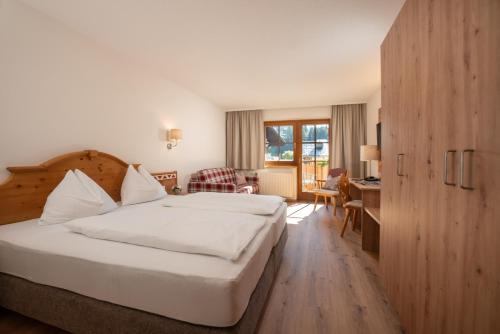 ein Hotelzimmer mit einem großen Bett und einem Schreibtisch in der Unterkunft Hotel am Sonnenhügel in Filzmoos