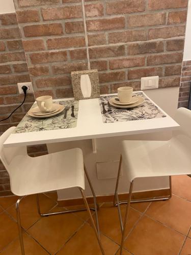 a white table and chairs with cups and saucers on it at Saffi58 Holiday Home in Viterbo