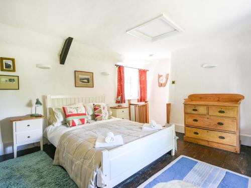 1 dormitorio con cama blanca y tocador de madera en Old Cross Cottage, en Whitchurch Canonicorum
