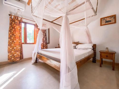 a bedroom with a bed with a canopy at Villa Samawati - Rafiki Village in Watamu