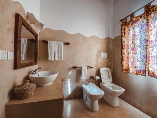 a bathroom with a sink and a toilet and a mirror at Villa Samawati - Rafiki Village in Watamu