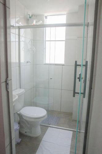 a bathroom with a toilet and a glass shower door at AP c ESTACIONAMENTO 900m do centro, prédio com piscina, sauna e academia in São João del Rei