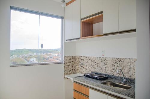 a kitchen with a sink and a window at Studio 900m do centro, prédio com piscina, sauna, academia e lavanderia in São João del Rei
