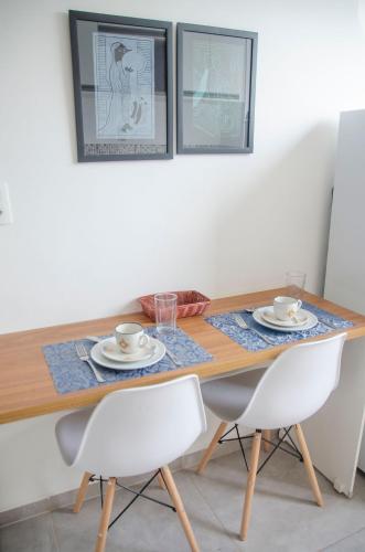 a dining room table with two chairs and two cups and plates at AP c ESTACIONAMENTO 900m do centro, prédio com piscina, sauna e academia in São João del Rei