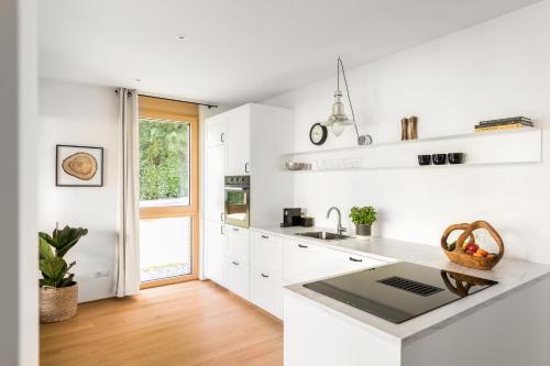 eine weiße Küche mit weißen Schränken und einem Fenster in der Unterkunft Ferienwohnung Rosenstrasse in Dornbirn