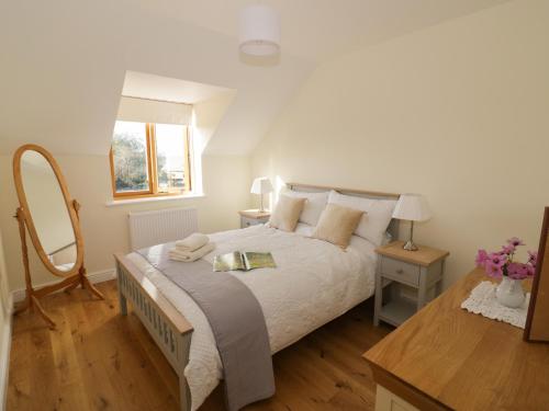 a bedroom with a large bed and a mirror at Granary Cottage in Southam