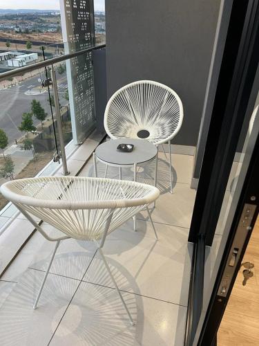 two white chairs and a table on a balcony at Ellipse Apartment in Midrand