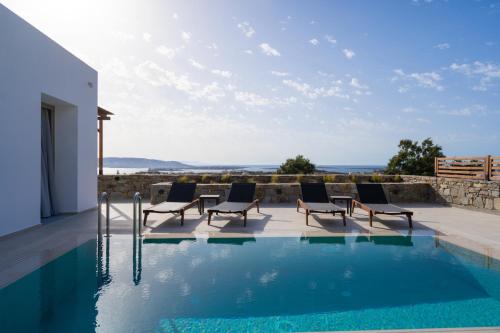 a swimming pool with chairs next to a house at Kouros Blanc Resort & Suites in Pounda