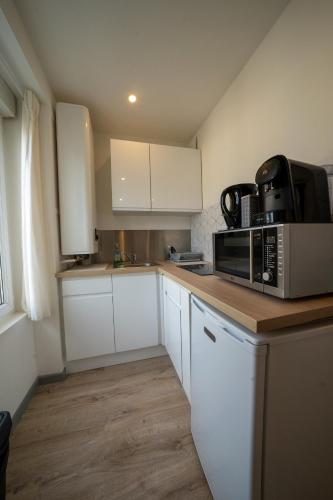 une cuisine avec des placards blancs et un four micro-ondes sur un comptoir dans l'établissement La merveille de Rochebonne 2, à Saint-Malo