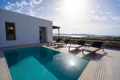 une piscine avec des chaises longues et une maison dans l'établissement Kouros Blanc Resort & Suites, à Pounda