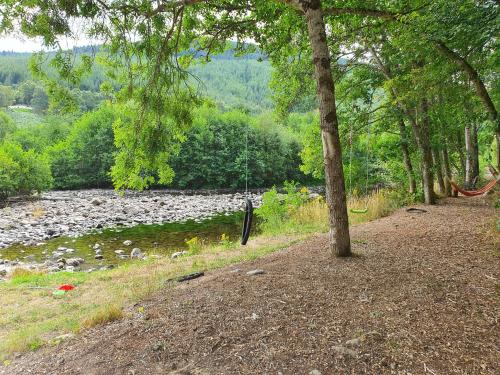a path next to a river with rocks and trees at Herons Rest in Drumnadrochit