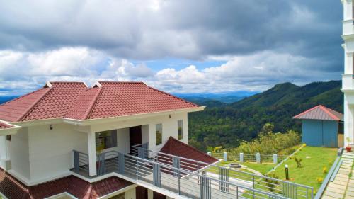 a house with a balcony with a view of the mountains at The Windy Mist Resort Munnar in Chinnakanal