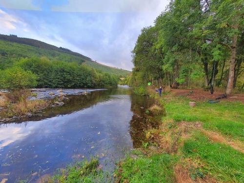 a river with a person walking on the side of it at Herons Rest in Drumnadrochit