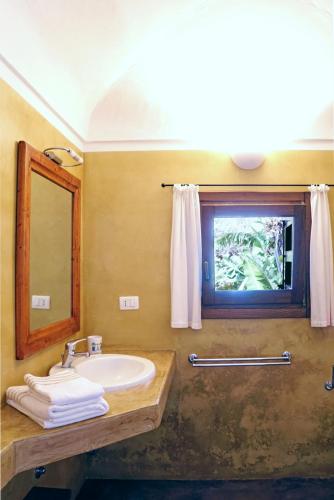 a bathroom with a sink and a mirror and a window at Dammusi I Jardina in Pantelleria