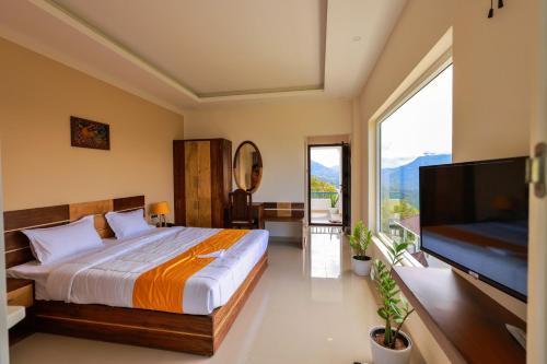 a bedroom with a large bed and a flat screen tv at The Windy Mist Resort Munnar in Chinnakanal