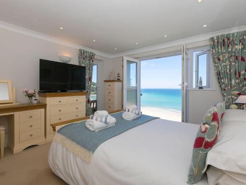 a bedroom with a large bed with a view of the ocean at Surf and Sand in St Ives