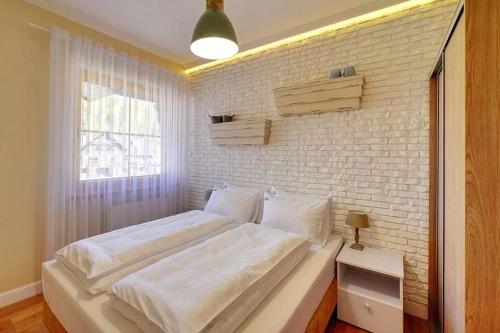 un letto bianco in una stanza con un muro di mattoni di Dolina Wikingów 2-poziomowy apartament w Norweskiej Dolinie a Szklarska Poręba