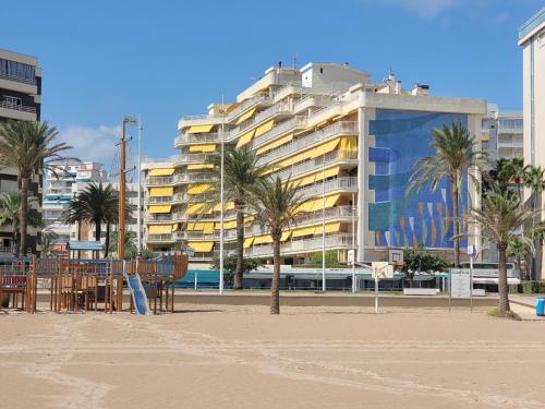ein Gebäude am Strand mit Palmen und Stühlen in der Unterkunft Aguamarina Gandia in Playa de Gandia