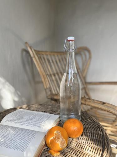 a bottle and two oranges and a book on a table at Maison H Guest House in Durban