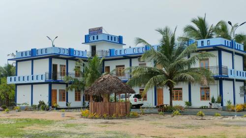 a blue building with palm trees in front of it at Victory's Gardens in Mannar