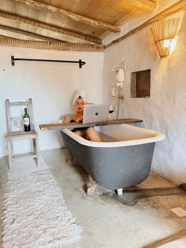 a woman sitting in a bath tub with a laptop at Loft Trancoso com Piscina & Jacuzzi in Trancoso
