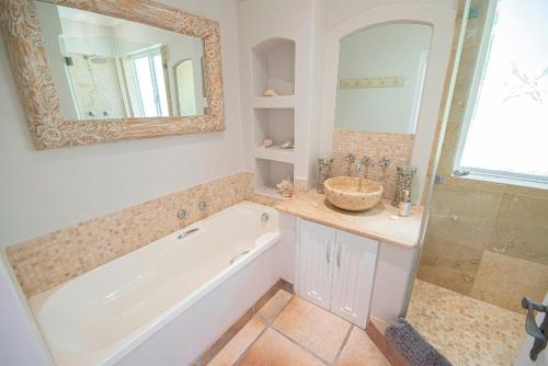 a bathroom with a tub and a sink and a mirror at Lavender hill in Plettenberg Bay
