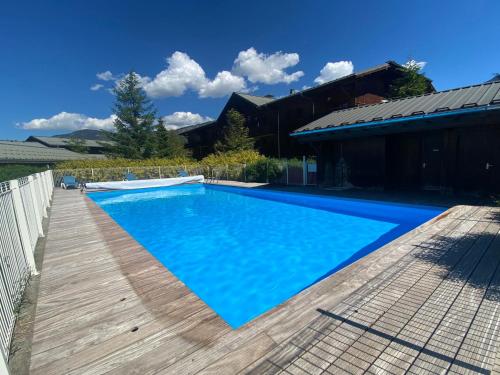 une piscine avec une terrasse en bois à côté d'une maison dans l'établissement Appartement T3 avec piscine, terrasse et parking à Samoëns, proche centre et ski-bus - FR-1-624-63, à Samoëns