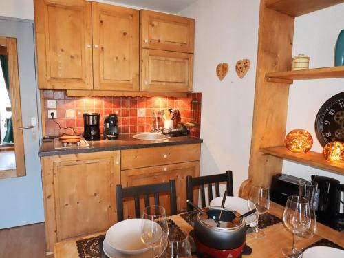 une cuisine avec des armoires en bois et une table avec des chaises dans l'établissement Charmant studio rénové au centre de Samoëns, avec balcon, parking et accès bus à 150m - FR-1-624-106, à Samoëns