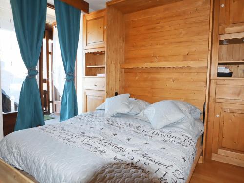 - une chambre avec un lit et un mur en bois dans l'établissement Charmant studio rénové au centre de Samoëns, avec balcon, parking et accès bus à 150m - FR-1-624-106, à Samoëns