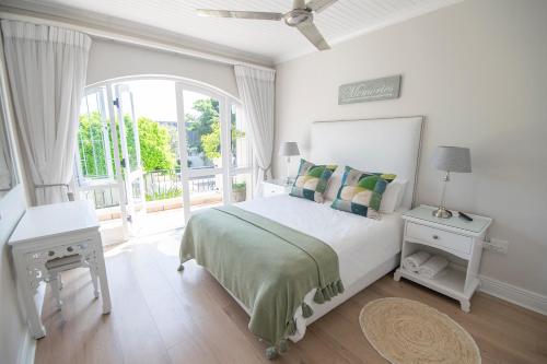 a white bedroom with a bed and a large window at Lavender hill in Plettenberg Bay