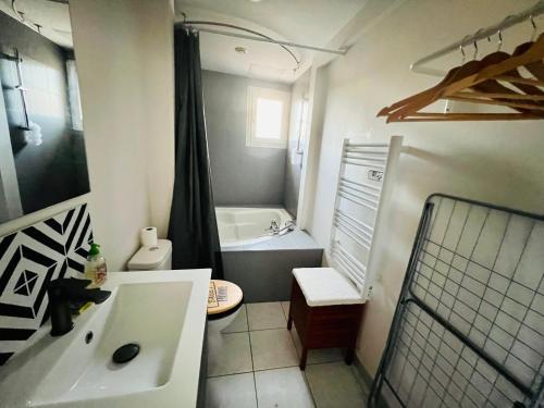 a bathroom with a tub and a sink and a toilet at La Plume Wifi Parking Un-Séjour-à-Part in Clouange