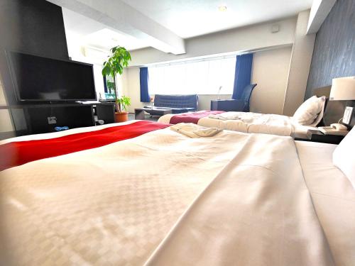 a bedroom with two beds and a flat screen tv at Kurume Hotel Esprit in Kurume