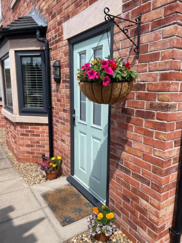 a door with a basket of flowers on a brick house at Abbey’s Inn in Cheadle