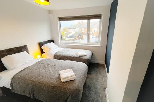 two beds in a small room with a window at Incredible house for Work teams & Holiday stays in Cleethorpes