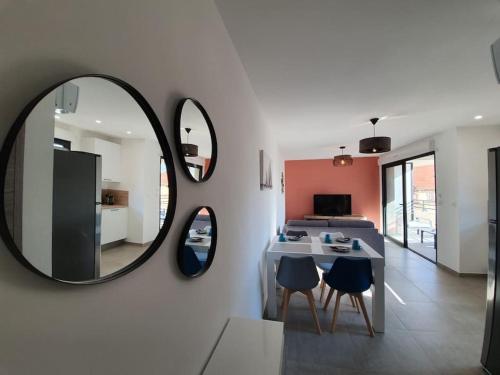 een woonkamer met een spiegel en een tafel en stoelen bij Appartement neuf très lumineux avec parking in Argelès-sur-Mer