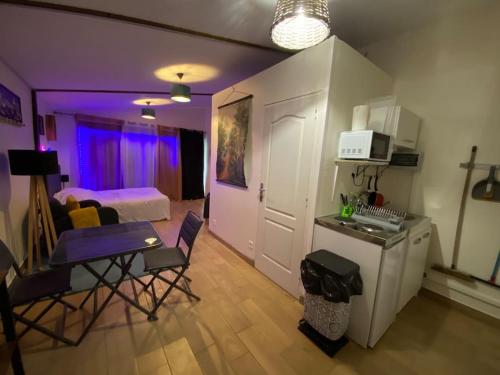 Habitación con cocina y dormitorio con iluminación púrpura. en Cocoon Room - jacuzzi, en Sémoy