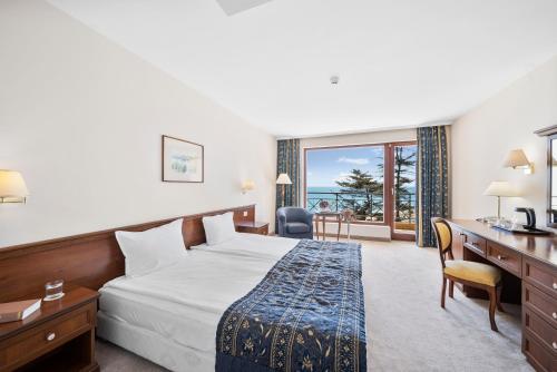 a hotel room with a bed and a desk and a window at Riviera Beach Hotel & SPA, Riviera Holiday Club - All Inclusive & Private Beach in Golden Sands